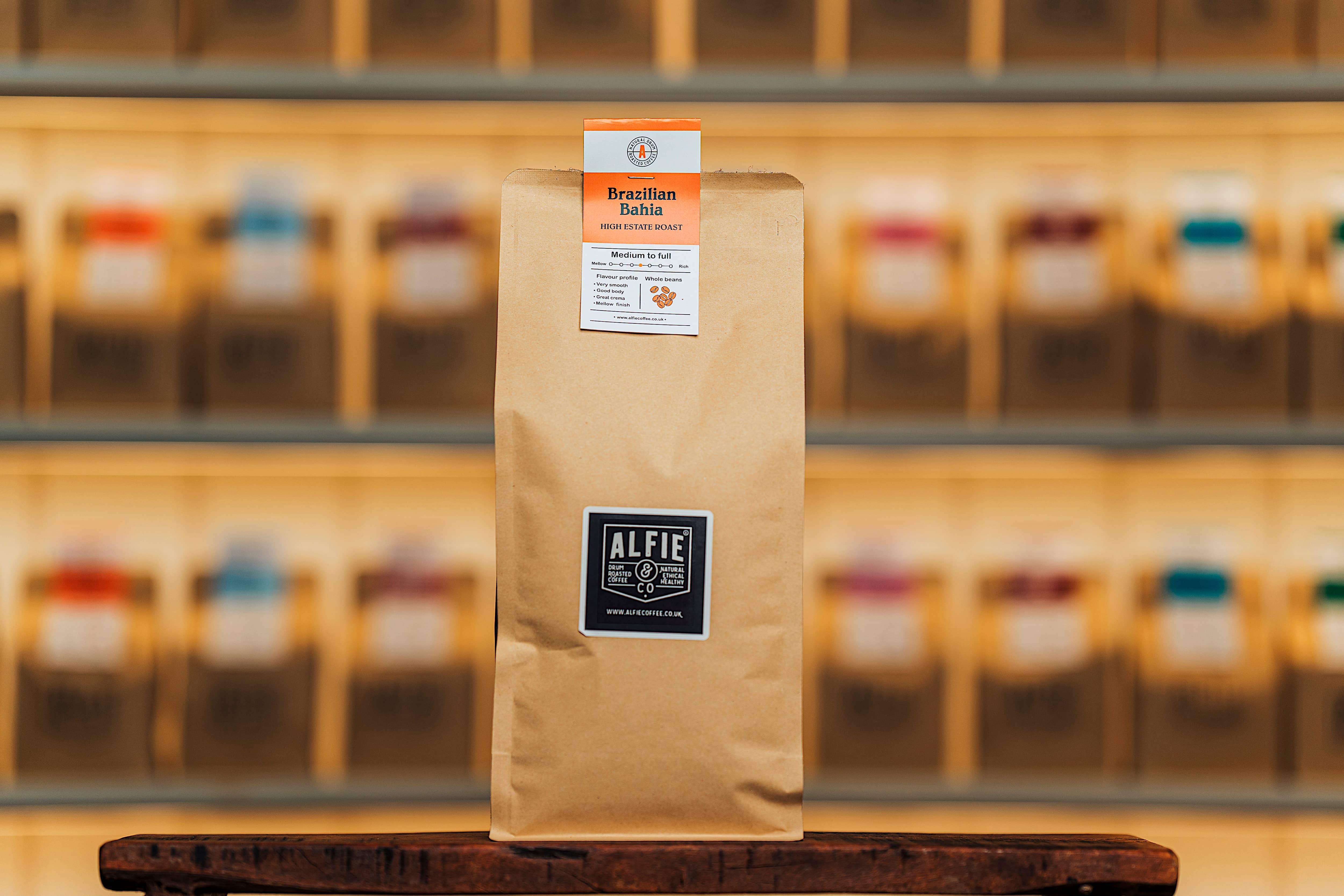 Alfie & Co Coffee Roasters – Brazilian Bahia whole-bean coffee in 1kg kraft packaging, displayed on a wooden counter with softly blurred roastery shelves behind.